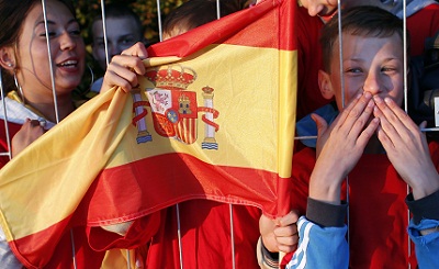 Local fans hold a Spain flag as the Spanish soccer team arrive at their training base in Gniewino